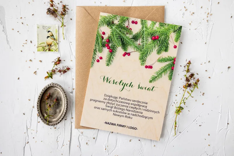 Drewniana kartka świąteczna z grafiką zielonych gałązek, personalizowana dla firm z ich logo i treścią życzeń.