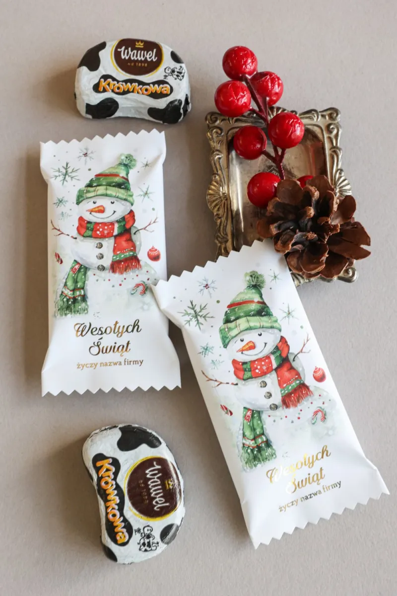 Świąteczne czekoladki w białym opakowaniu z grafiką uśmiechniętego bałwana w zielonej czapce i szaliku. Świąteczne czekoladki w białym opakowaniu z grafiką uśmiechniętego bałwana w zielonej czapce i szaliku.