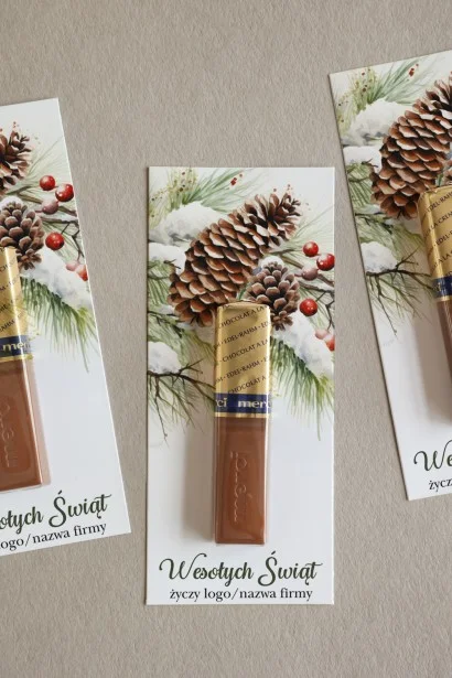 Eleganckie czekoladki Merci w personalizowanym opakowaniu ze świąteczną grafiką przedstawiającą szyszki i gałązki