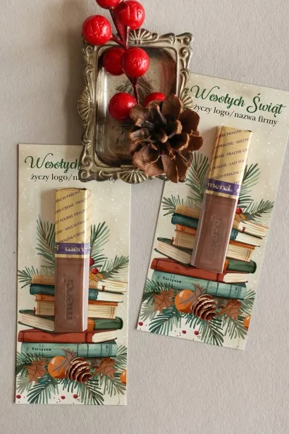 Firmowe czekoladki Merci z akwarelową grafiką świątecznych dekoracji i książek, idealne na świąteczne upominki.
